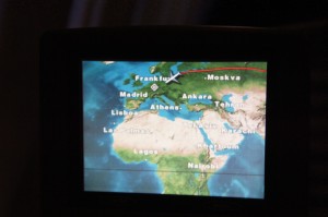 The image shows an in-flight entertainment screen displaying a flight path map. The map highlights various cities including Frankfurt, Madrid, Athens, Ankara, Tehran, Moscow, Lagos, and Nairobi. An airplane icon is shown flying over Europe, indicating the current position of the flight.