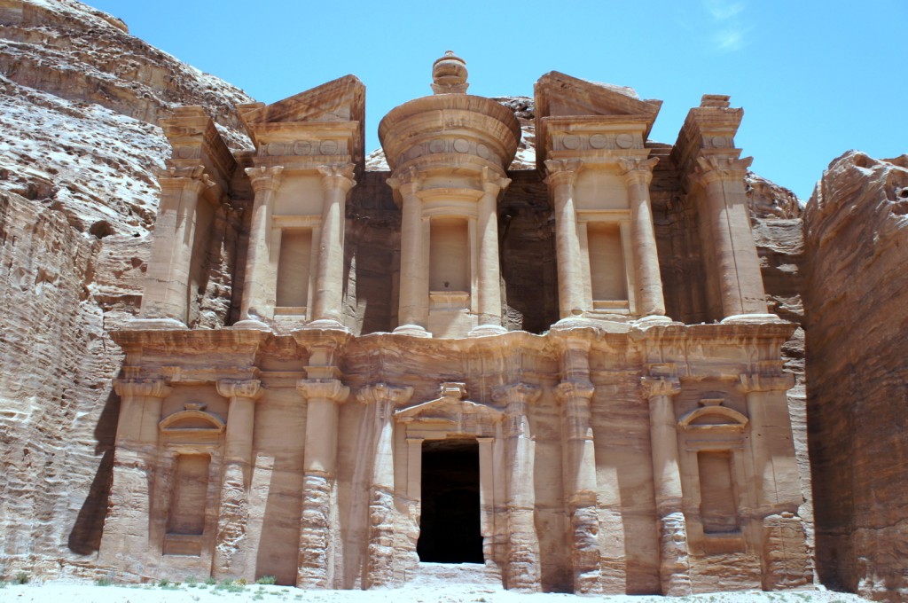 a stone building with columns with Petra in the background