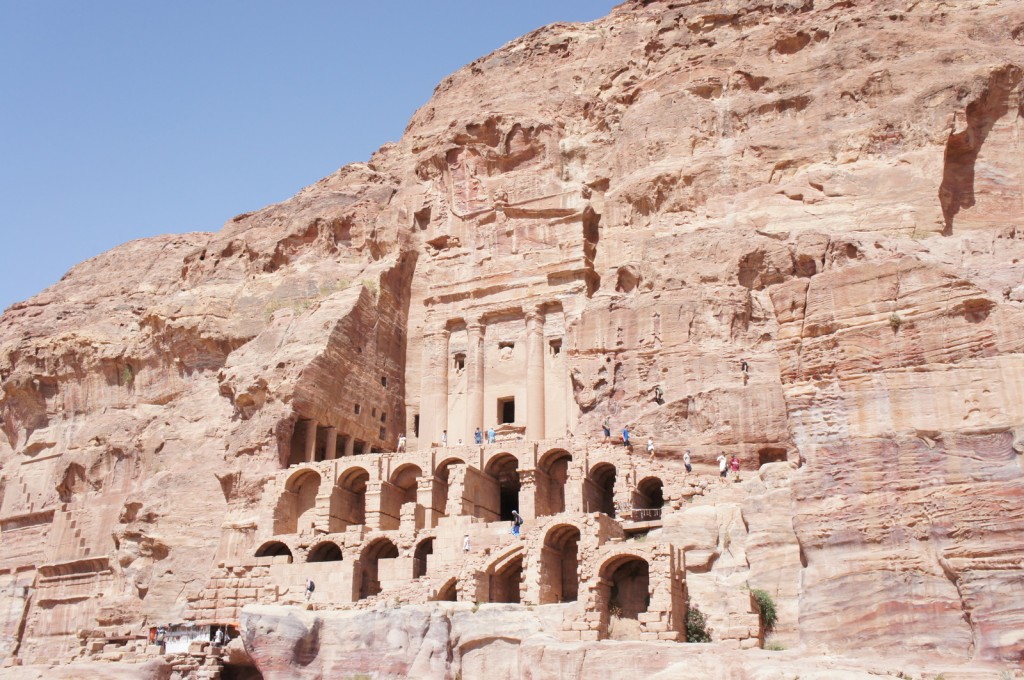 a stone structure in a cliff with Petra in the background