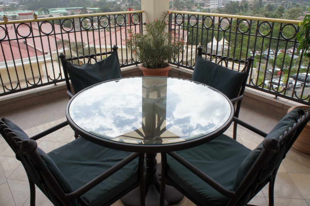 a glass table with chairs on a balcony