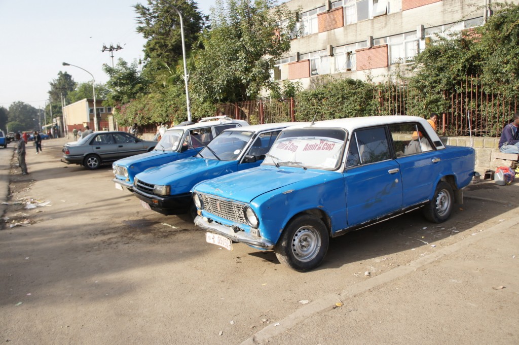 a group of blue cars parked on a street