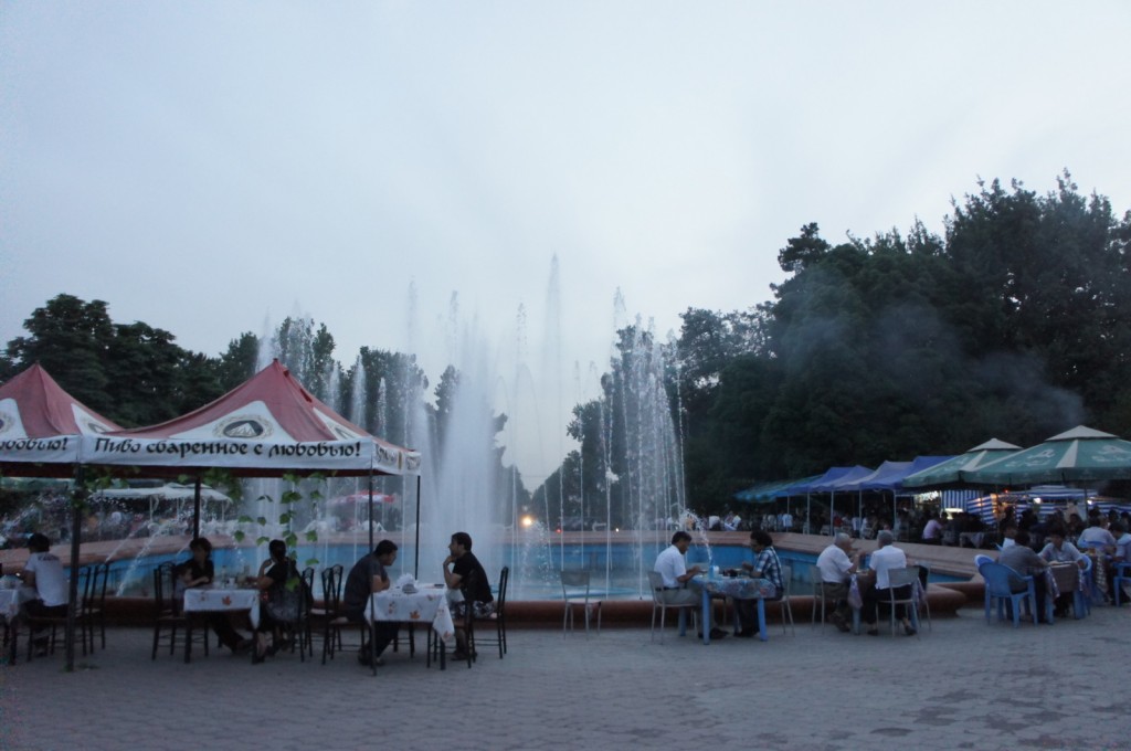 people sitting at tables in front of a fountain