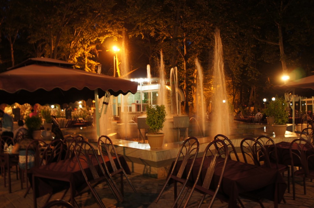 a fountain with tables and chairs in front of it