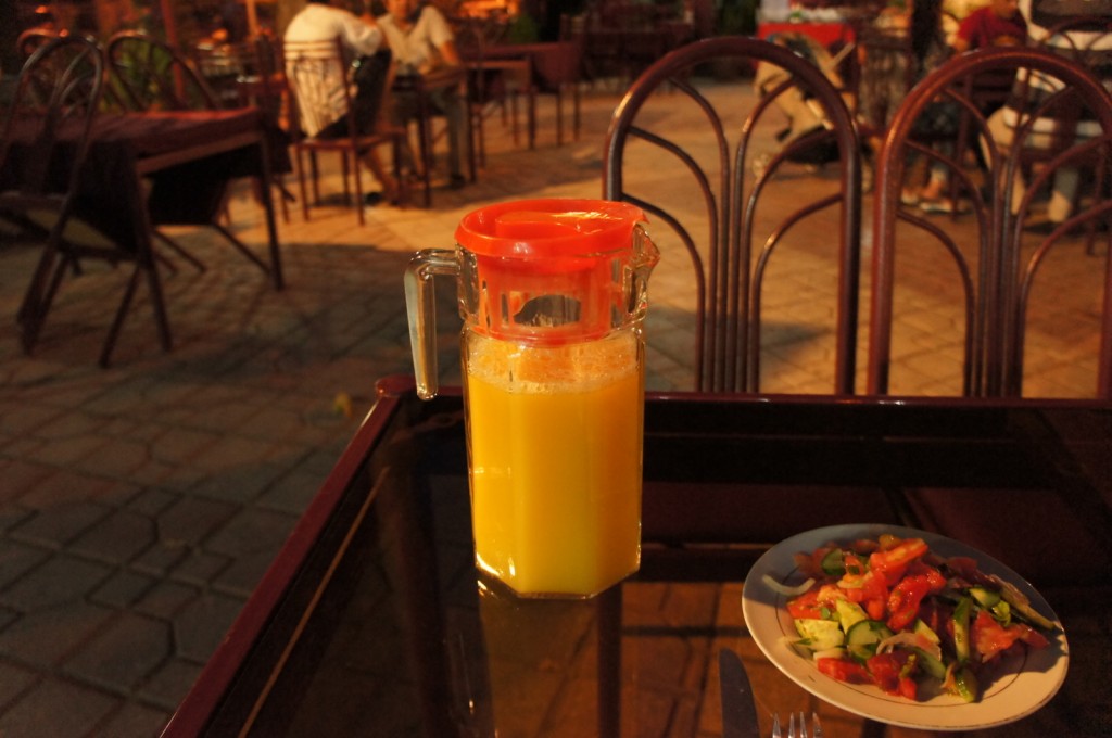 a pitcher of orange juice on a table with a plate of food