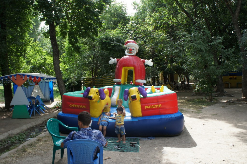 a group of kids sitting in chairs outside by a inflatable bouncy castle