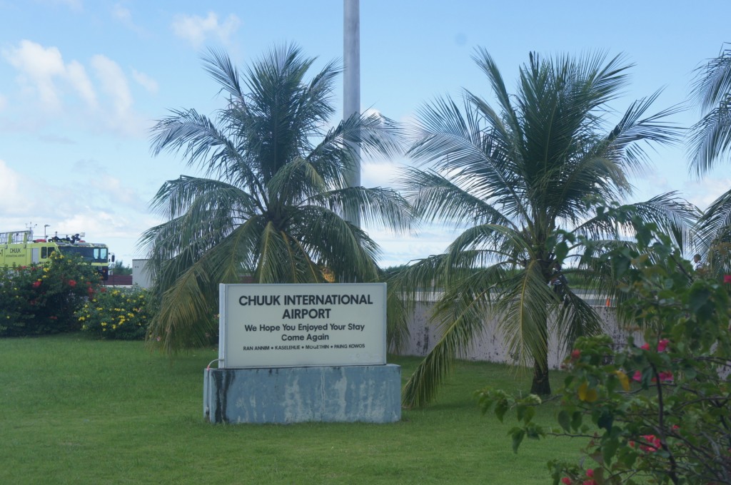 a sign in front of palm trees