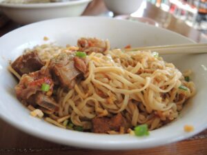 a bowl of noodles with meat and vegetables