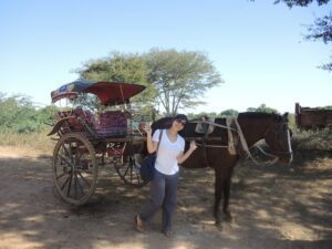a woman standing next to a horse carriage