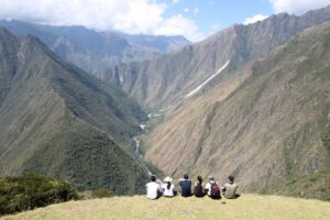 a group of people sitting on a hill looking at a valley