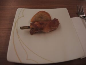 a piece of meat on a stick on a white plate