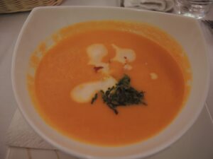 a bowl of soup with cream and green garnish