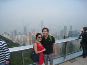 a man and woman standing on a balcony with a city in the background
