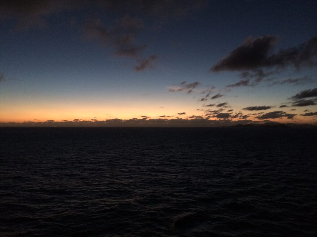 a body of water with clouds and a sunset