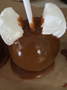 a caramel apple with marshmallows and a straw