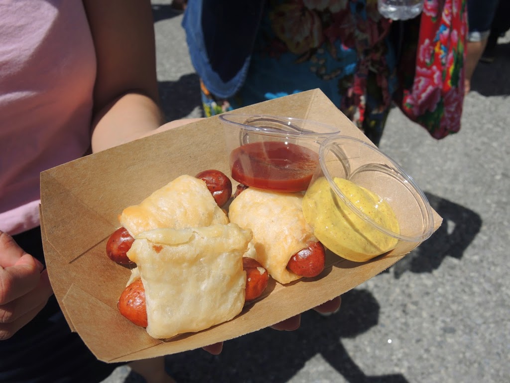 a person holding a plate of hot dogs wrapped in dough