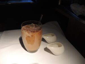 a glass of coffee with a straw and a spoon