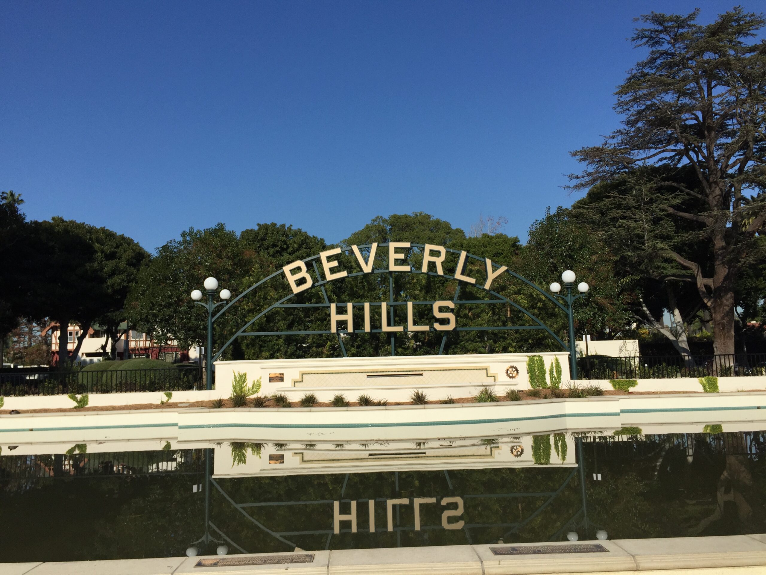 a sign over a pool with trees in the background