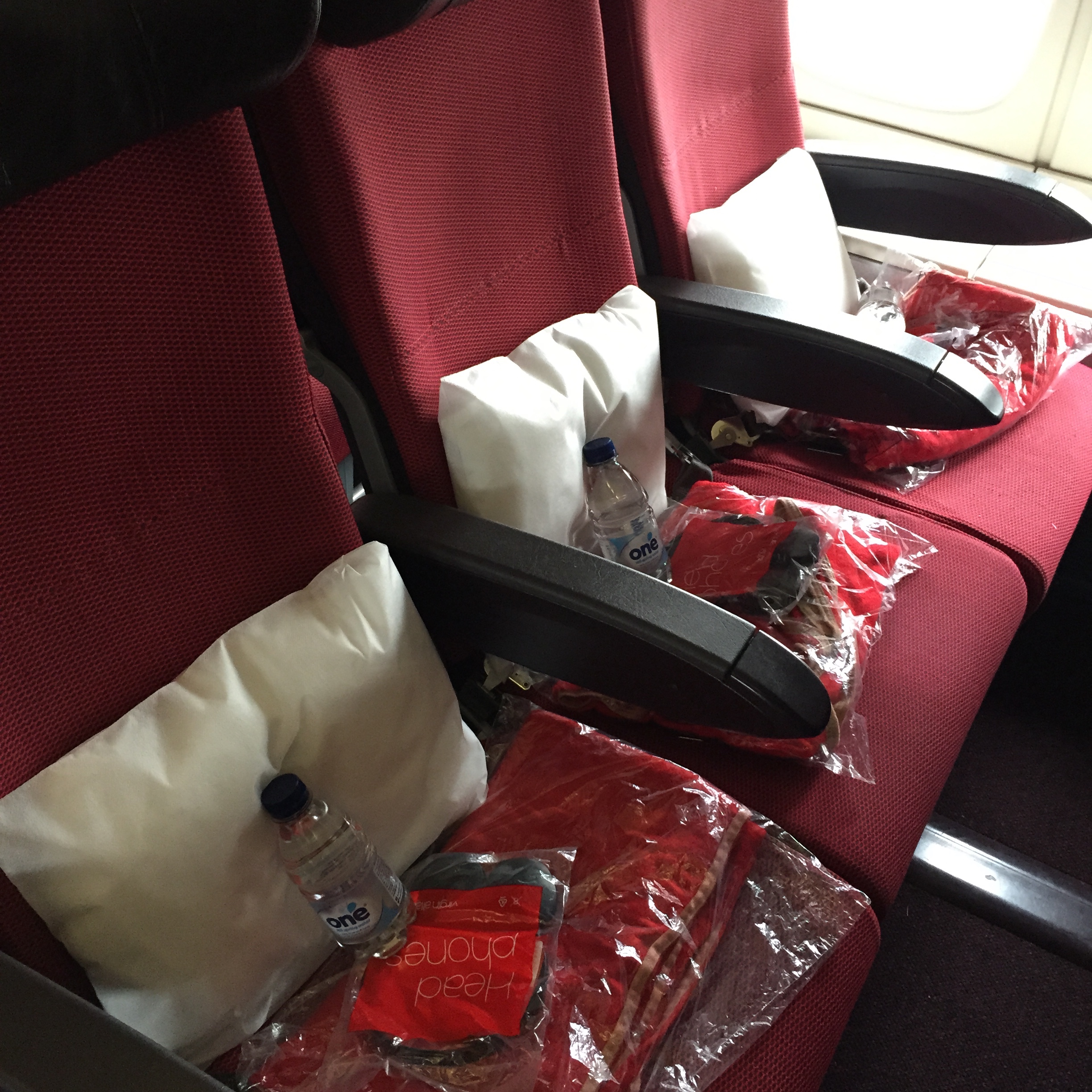 a row of red seats with plastic bags and a bottle of water