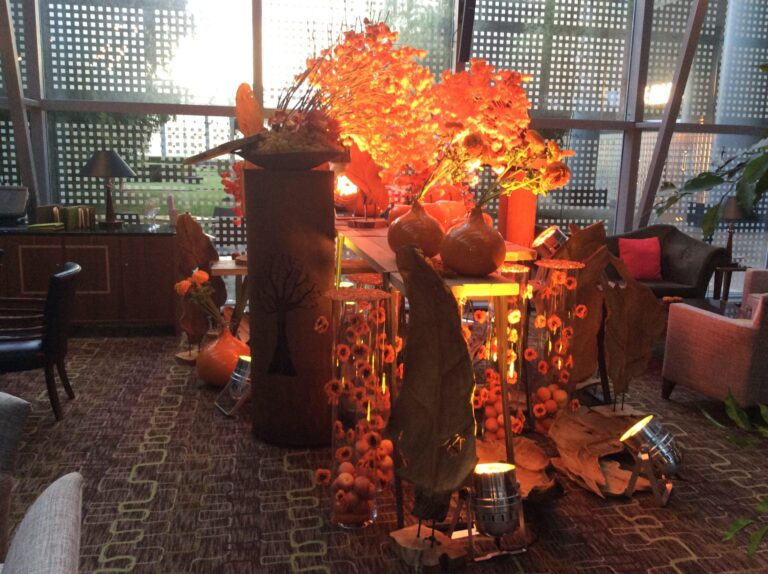 a table with orange leaves and vases