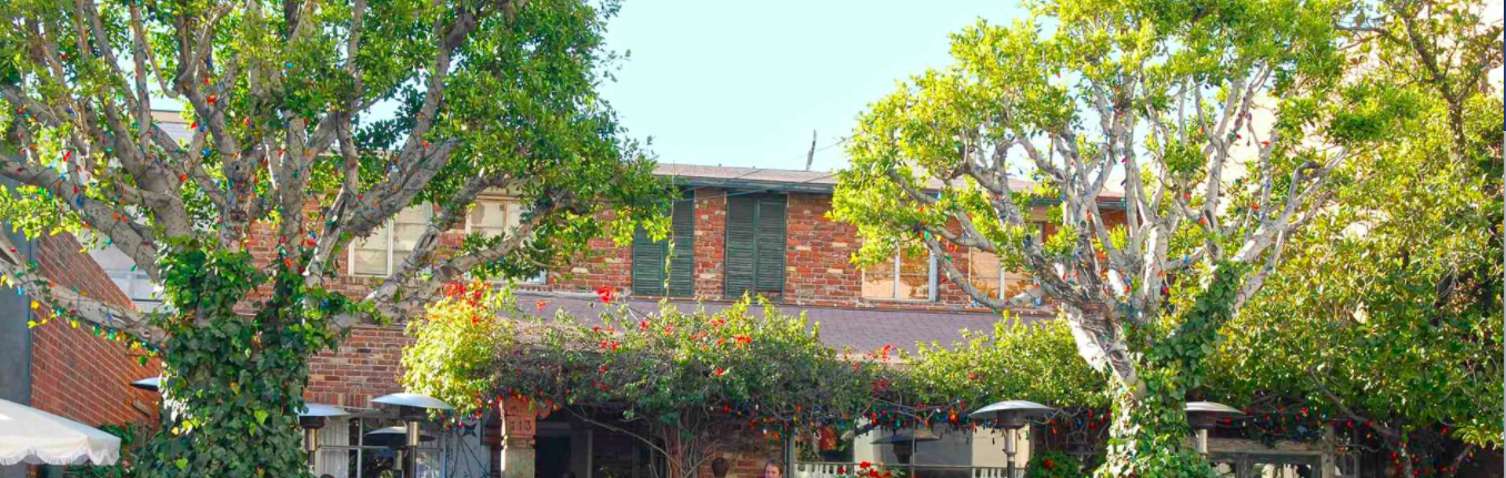 a brick building with trees and a building with a roof