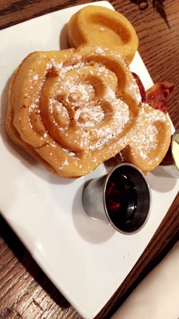 a plate of food with a cup of liquid and a waffle in the shape of a rose