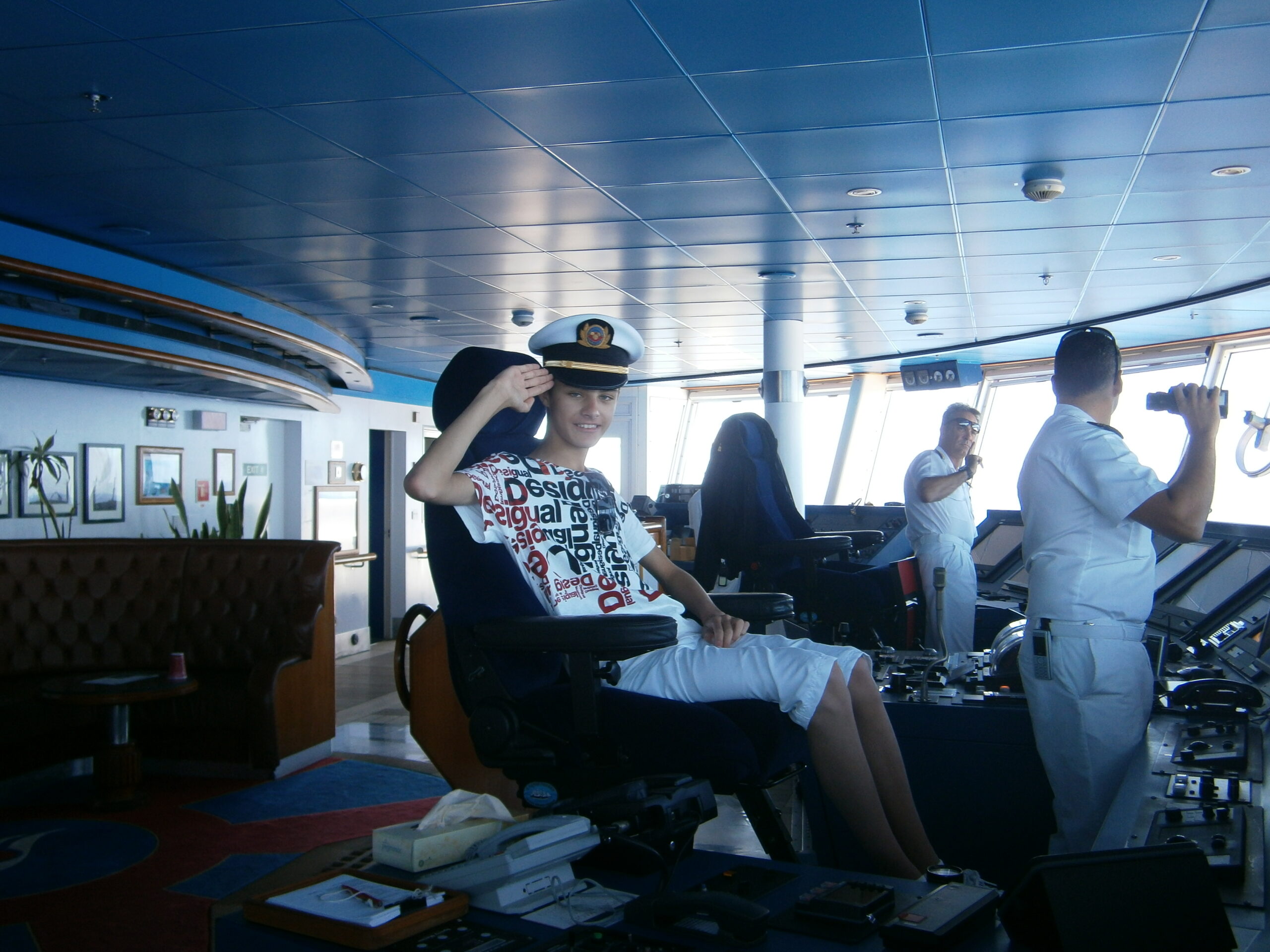 a boy in a hat saluting in a ship